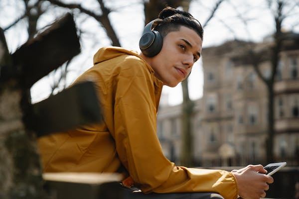 Teen boy with headphones staring into the distance while on his phone